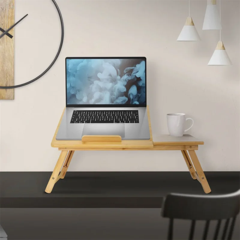 Ein klappbarer Tisch aus Bambus mit einem Laptop und einer Tasse.