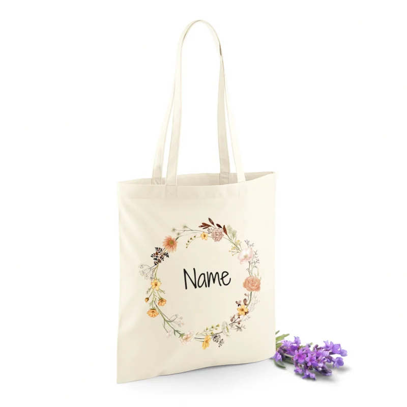 Beige Stofftasche mit floralem Muster und Platz für Namen.