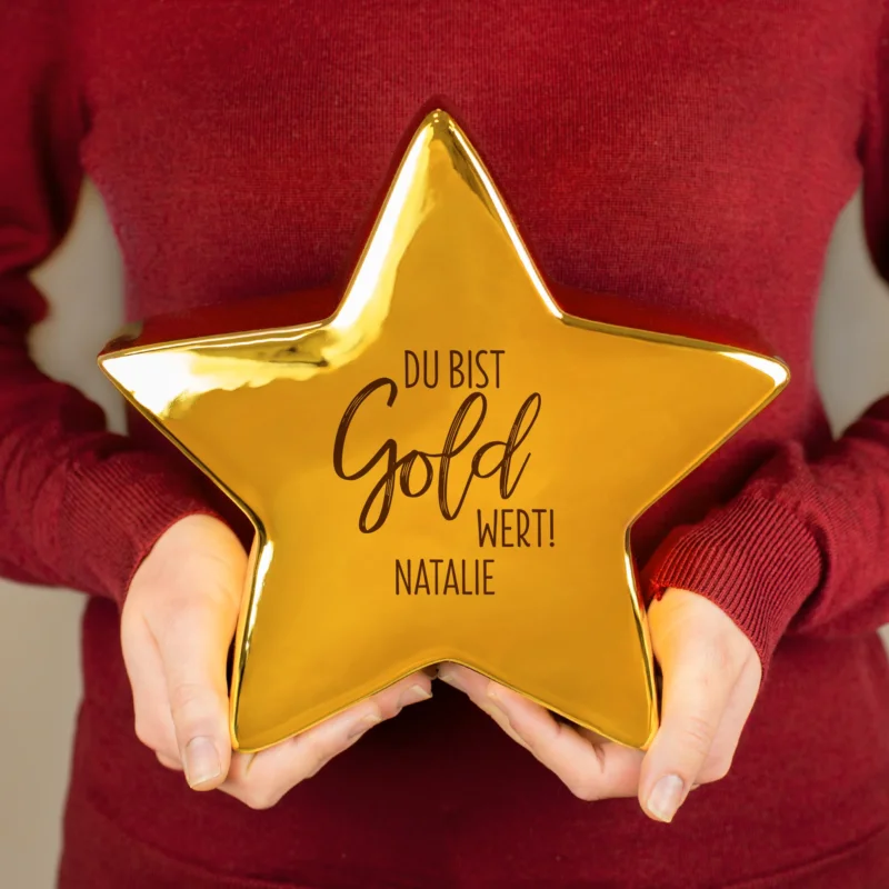 Goldfarbener Keramikstern von Leonardo mit Motiv „Du bist Gold wert!“ und personalisiertem Namen – in der Hand